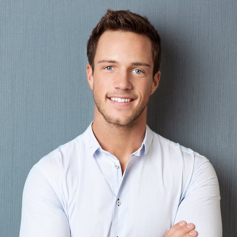 Joven hombre sonriente con camisa blanca, modelo profesional para bienes raíces comerciales, imagen para fichas de propiedades en fompo.com.