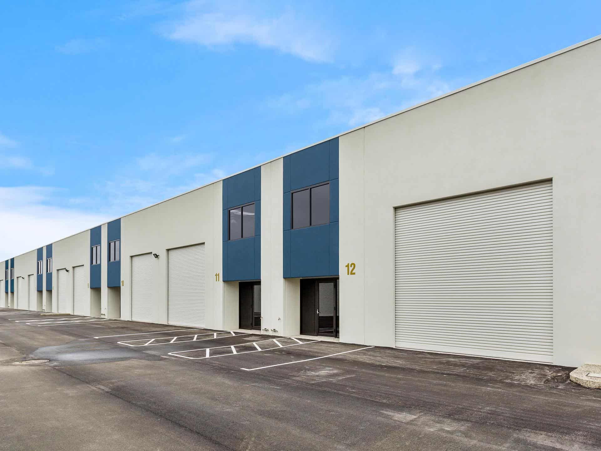 Alt: Fábrica o almacén en un parque industrial, ideal para negocios y comercio, con amplios espacios y puertas de garaje automatizadas en una zona moderna y bien ubicada.