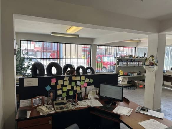 Alt: Espacio de oficina con escritorio lleno de papeles, teléfono y computadora en ambiente de bienes raíces comerciales.