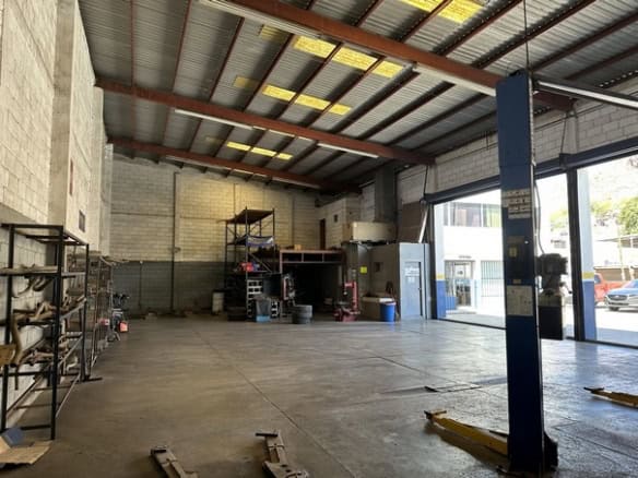 Alt text: Espacio industrial o almacén en venta o alquiler con amplio interior, estructura de techos altos y zona de carga y descarga, ideal para negocios comerciales o logística.