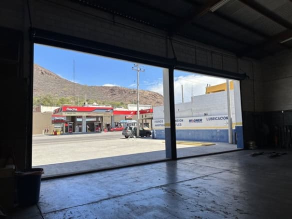 Tan solo el alt: vista de un establecimiento de servicio en la calle, visible desde el interior de un local vacío y oscuro.