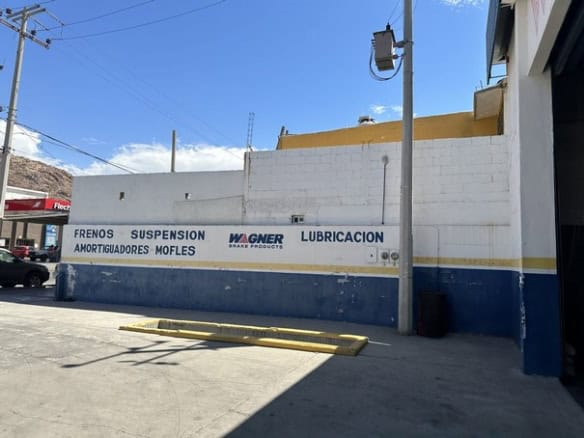 Mural exterior de taller de reparación de vehículos con señalización de servicios automotrices en un establecimiento comercial.