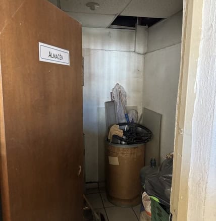 Almacén pequeño en espacio de oficina o local comercial, con objetos y material guardado, en entorno interior.