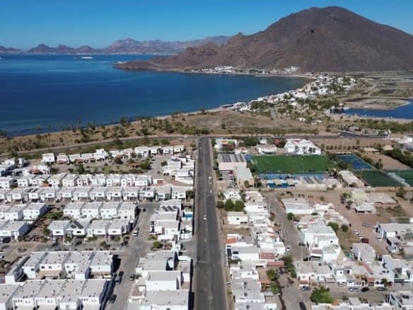 Alt text: Vista aérea de bienes raíces comerciales en Fompo con viviendas, áreas verdes y accesos cerca del lago y montañas en la región de Fompo.