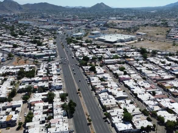 Amplia vista aérea de bienes raíces comerciales en clima urbano, mostrando desarrollos y parcelas en crecimiento en una zona con infraestructura moderna.