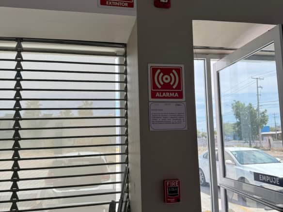 Puerta de cristal en propiedad comercial con señalización de alarma y extintor, ideal para negocios en búsqueda de seguridad y accesibilidad.