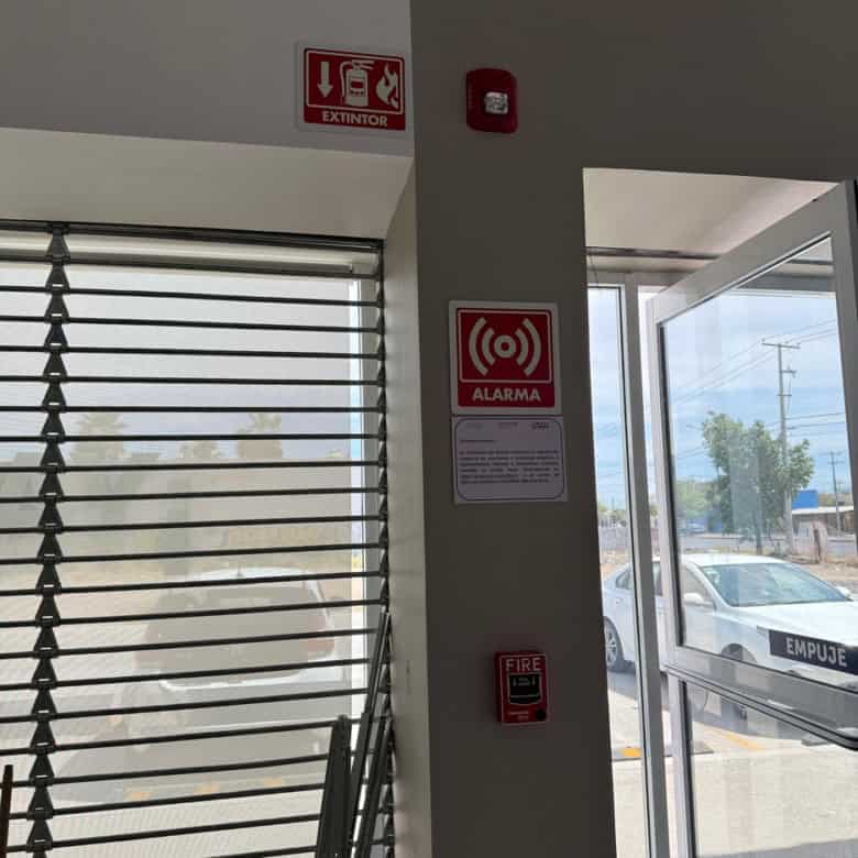 Puerta de cristal en propiedad comercial con señalización de alarma y extintor, ideal para negocios en búsqueda de seguridad y accesibilidad.