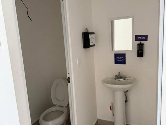 Acceso a baño en propiedad comercial, con lavabo y taza sanitaria, espacio limpio y funcional para uso comercial o institucional, ideal para locales en venta o renta.