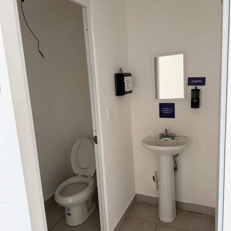 Acceso a baño en propiedad comercial, con lavabo y taza sanitaria, espacio limpio y funcional para uso comercial o institucional, ideal para locales en venta o renta.