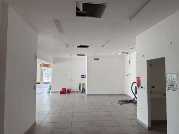 Amplia oficina en proceso de construcción comercial en Fompo Bienes Raíces. Espacio luminoso con paredes blancas, piso de baldosas y ventilación instalada. Ideal para negocio o inversión en bienes raíces comerciales.