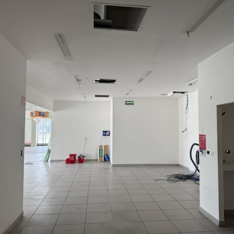 Amplia oficina en proceso de construcción comercial en Fompo Bienes Raíces. Espacio luminoso con paredes blancas, piso de baldosas y ventilación instalada. Ideal para negocio o inversión en bienes raíces comerciales.