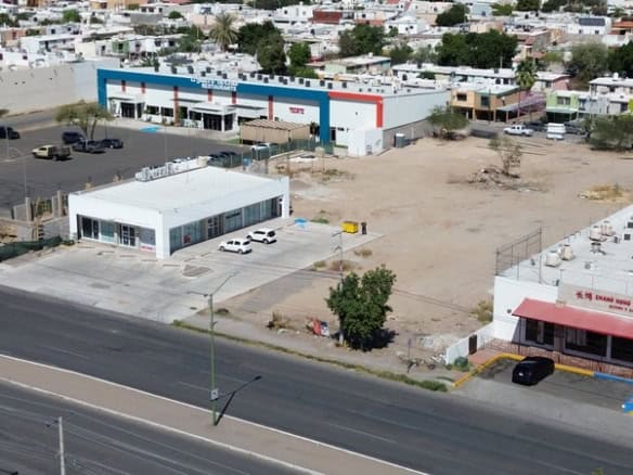 Alt text: Terreno comercial en venta en una zona urbana con edificios cercanos y fácil acceso vial.