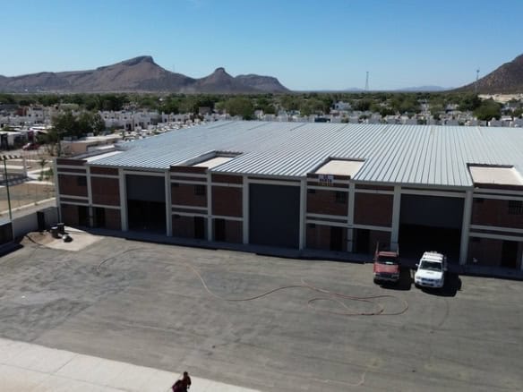 Alt: Imagen de un edificio industrial o almacén para bienes raíces comerciales en Fompo Bienes Raíces Comerciales, con amplio espacio de estacionamiento y fachada moderna.