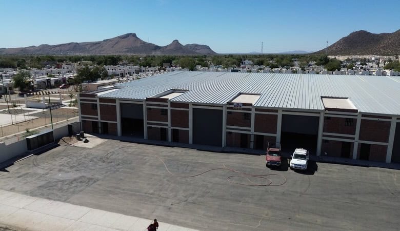 Alt: Imagen de un edificio industrial o almacén para bienes raíces comerciales en Fompo Bienes Raíces Comerciales, con amplio espacio de estacionamiento y fachada moderna.