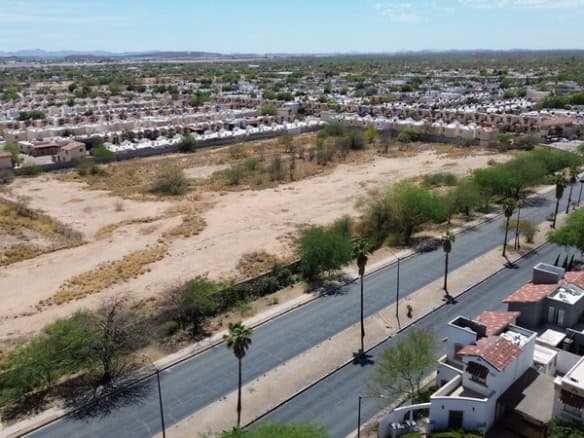 Terreno comercial ubicado en una zona en desarrollo con potencial para inversión inmobiliaria, rodeado de viviendas y accesos principales, ideal para proyectos de bienes raíces comerciales.