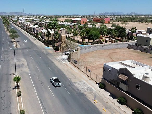 Vista aérea de una calle principal en una zona comercial, con edificios y espacios disponibles para inversión inmobiliaria, ideal para negocios y desarrollo comercial en Fompo.
