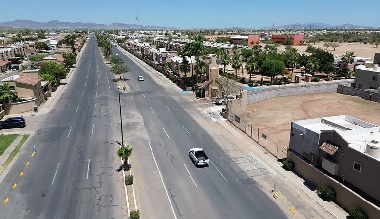 Vista aérea de una calle principal en una zona comercial, con edificios y espacios disponibles para inversión inmobiliaria, ideal para negocios y desarrollo comercial en Fompo.
