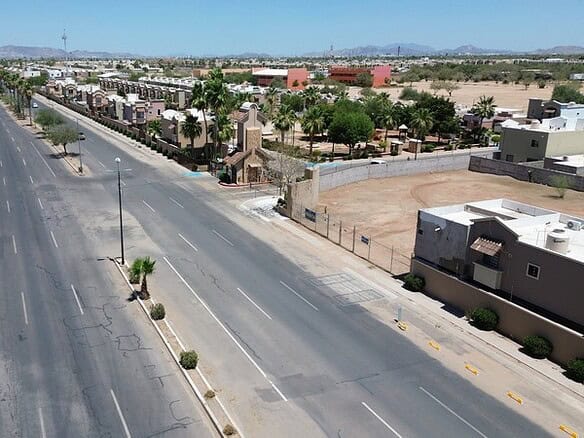 Imagen de una calle comercial en una zona urbana con propiedades en venta, mostrando un amplio espacio para negocios y desarrollo inmobiliario en una ciudad moderna.