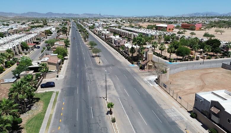 Vista aérea de una calle principal en una zona industrial con espacios comerciales y residenciales en un entorno árido, ideal para inversiones en bienes raíces comerciales en áreas urbanas.