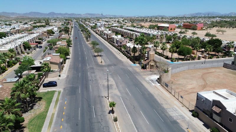 Fompo bienes raíces comerciales – Vista aérea de calle en zona industrial Vista aérea de una calle principal en una zona industrial con espacios comerciales y residenciales en un entorno árido, ideal para inversiones en bienes raíces comerciales en áreas urbanas.