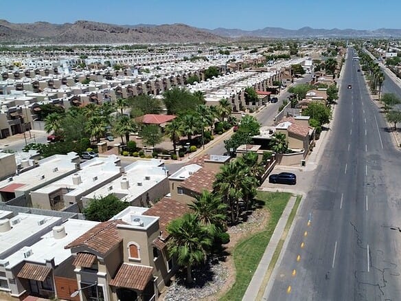 Vista aérea de espacios comerciales en un vecindario residencial en crecimiento, mostrando calles amplias, áreas verdes y edificios comerciales en un entorno urbano en expansión.