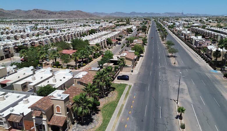Vista aérea de espacios comerciales en un vecindario residencial en crecimiento, mostrando calles amplias, áreas verdes y edificios comerciales en un entorno urbano en expansión.