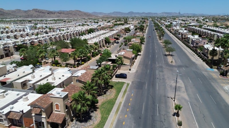 Espacios comerciales en desarrollo urbano Vista aérea de espacios comerciales en un vecindario residencial en crecimiento, mostrando calles amplias, áreas verdes y edificios comerciales en un entorno urbano en expansión.