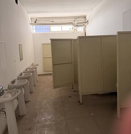 Baños públicos con urinarios y separadores, ideal para locales comerciales o espacios de alta afluencia en bienes raíces comerciales. Diseño funcional y limpio.