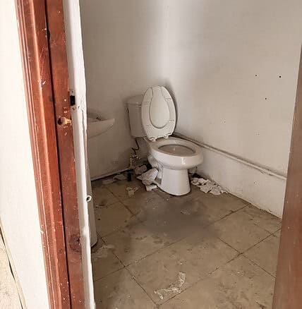 Sucia taza de baño en un espacio de oficina o local comercial con evidente deterioro y falta de mantenimiento.