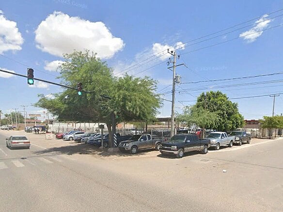 Imagen de un estacionamiento comercial en una calle de ciudad, con varios autos y árboles, ideal para inversión en bienes raíces comerciales.
