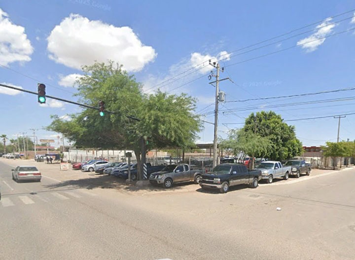 Imagen de un estacionamiento comercial en una calle de ciudad, con varios autos y árboles, ideal para inversión en bienes raíces comerciales.